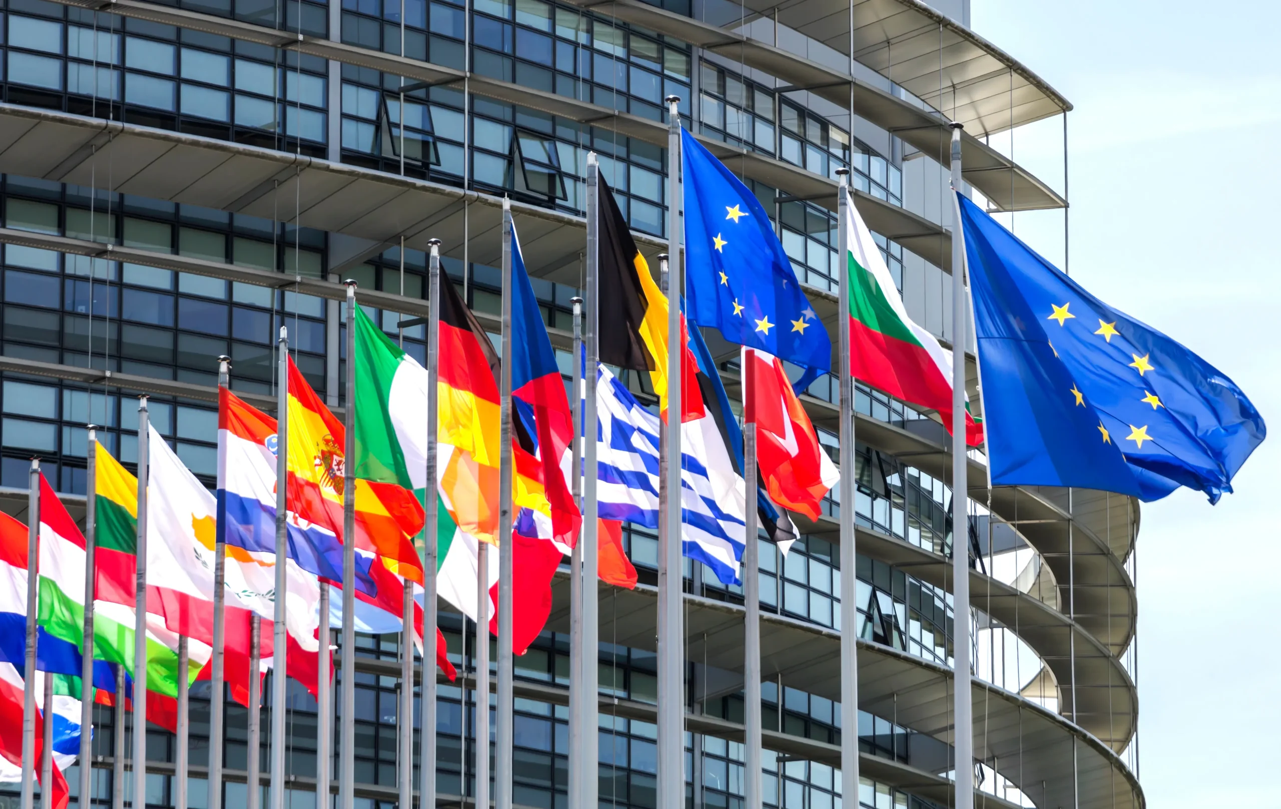 Flagi państw Unii Europejskiej przed budynkiem Parlamentu Europejskiego – kabotaż i cross-trade