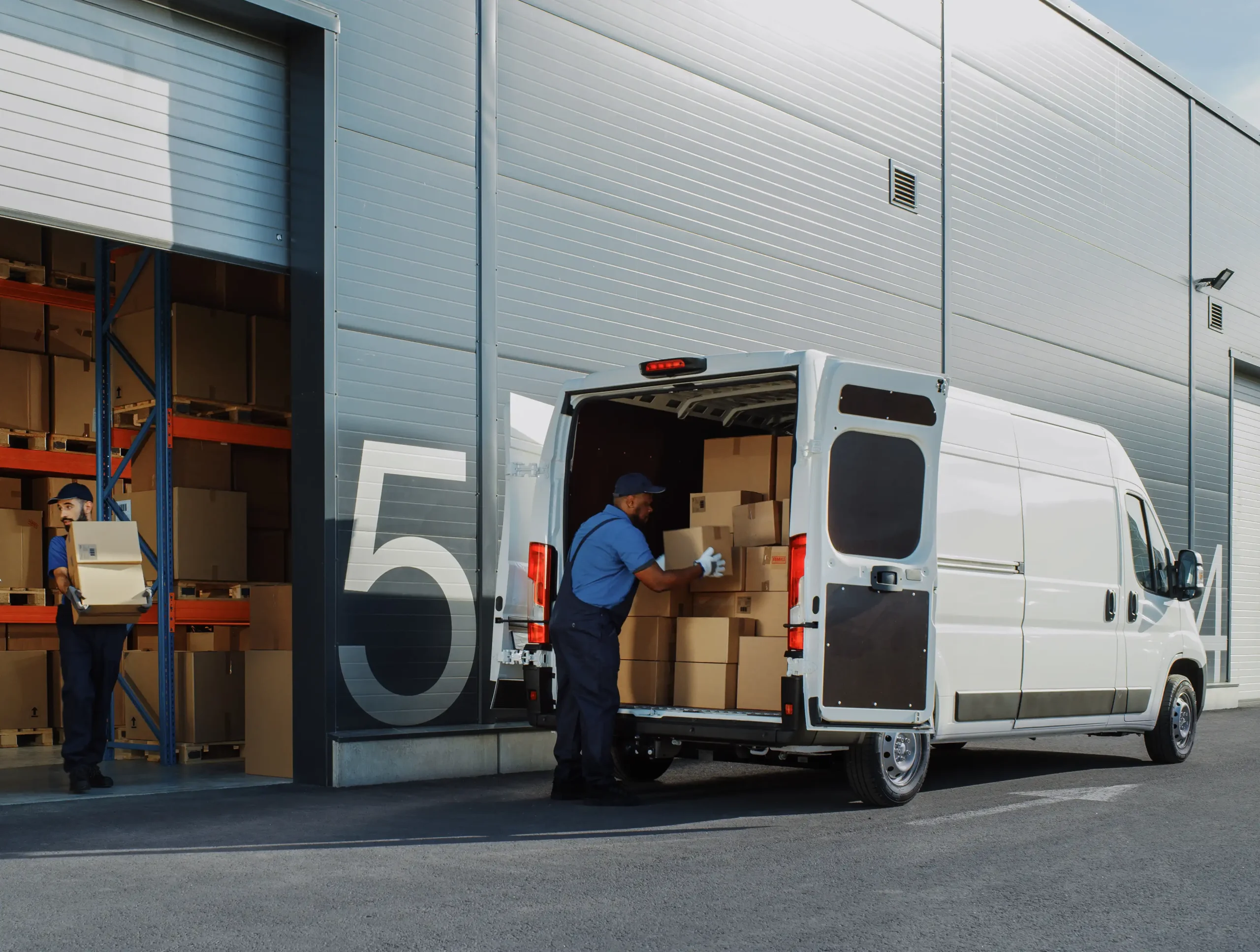 Bus dostawczy ładowany paletami z towarem w magazynie, symbolizujący efektywny transport LTL i FTL AMG Trans