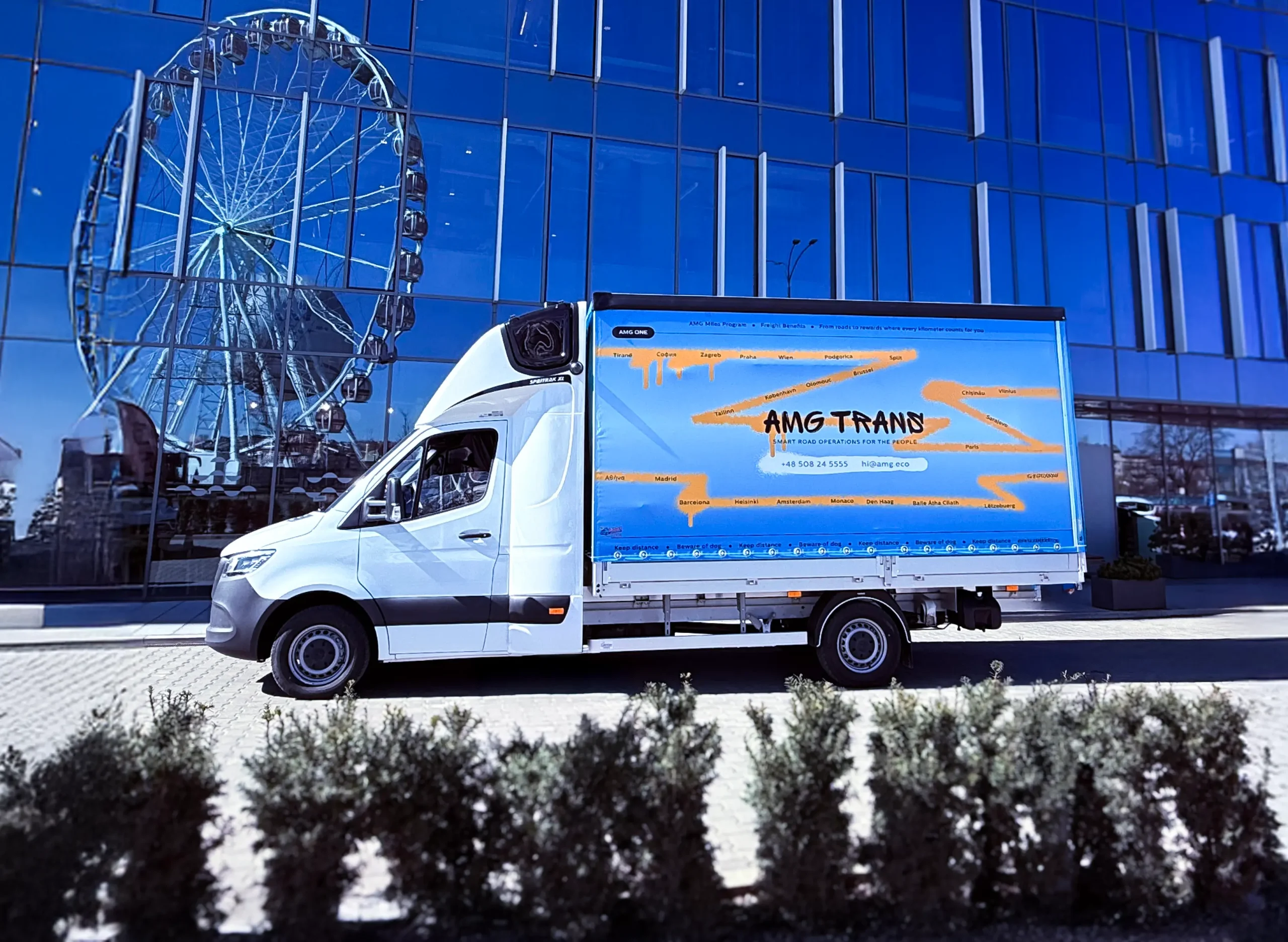 Bus AMG Trans przed nowoczesnym biurowcem – transport międzynarodowy na terenie UE