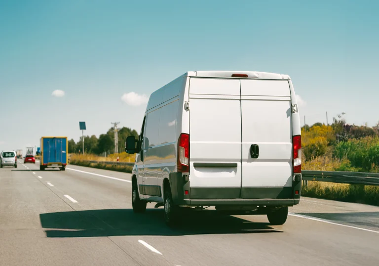 Bus dostawczy do 3,5 tony jadący drogą ekspresową w kierunku granicy, symbolizujący transport międzynarodowy.